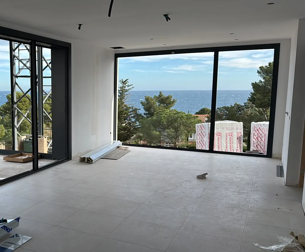 Salón de obra nueva con grandes correderas negras y vistas al mar